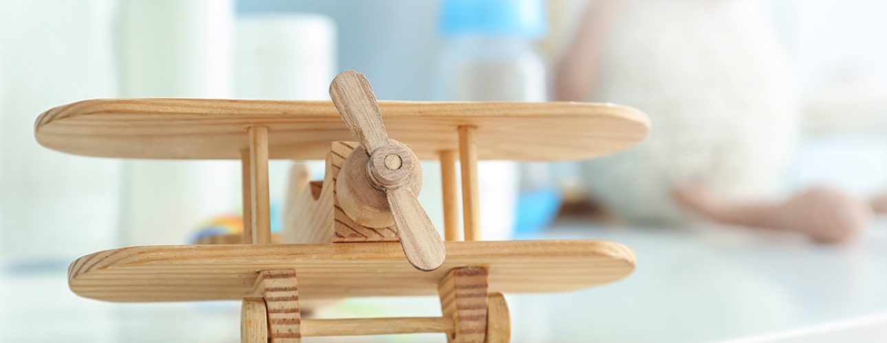 Baby girl with blue eyes wearing white towel or winter overal in white sunny bedroom. Newborn child relaxing in bed. Nursery for children. Textile and bedding for kids. New born kid with toy bear.